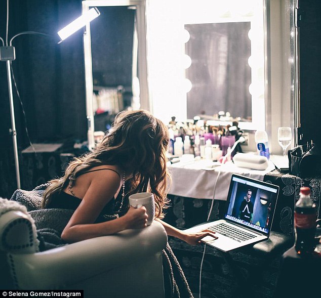 Selena uses computer near large mirror. 